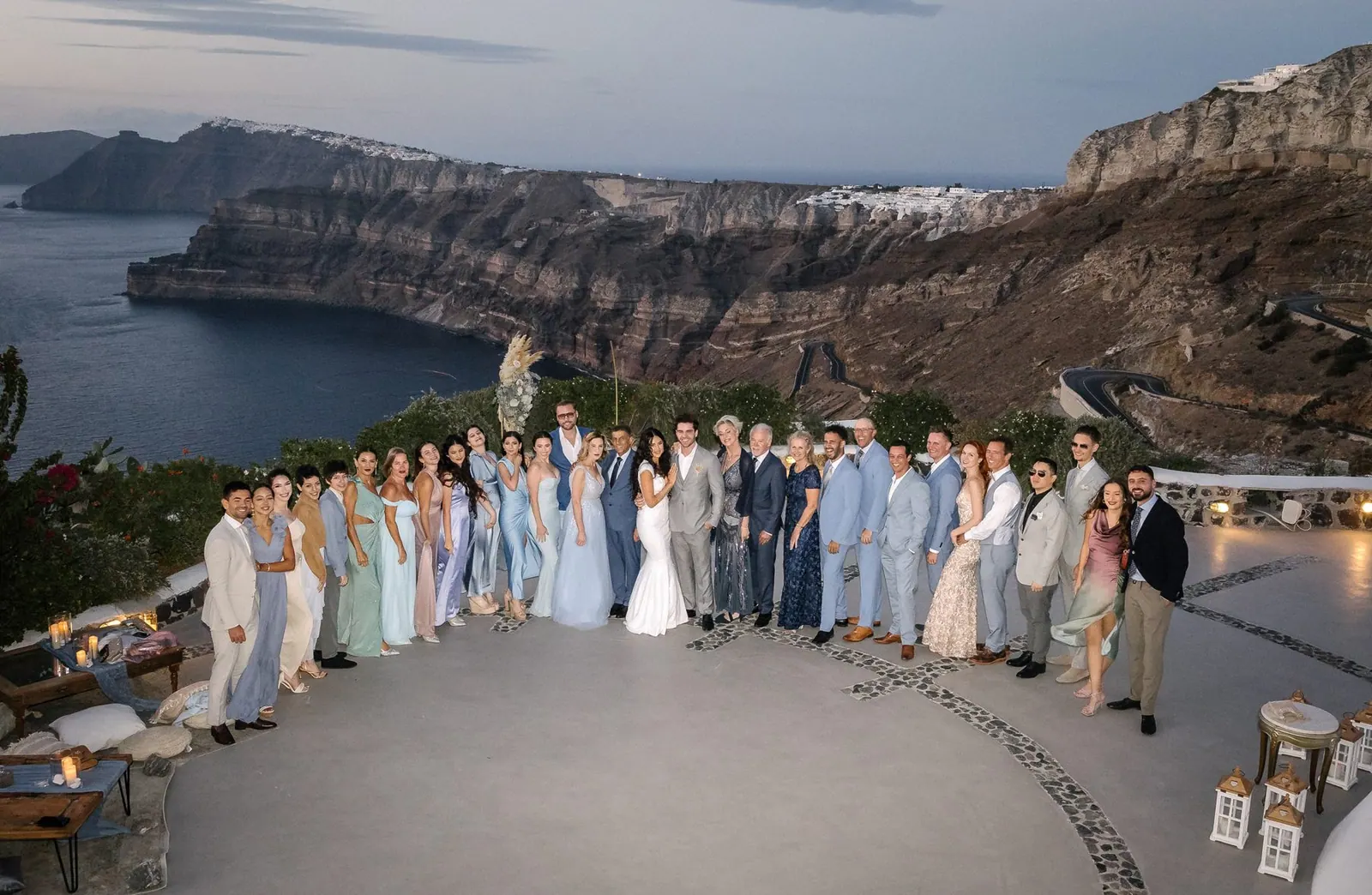 Couple and their wedding party on a clifftop terrace above the caldera in Santorini, Greece