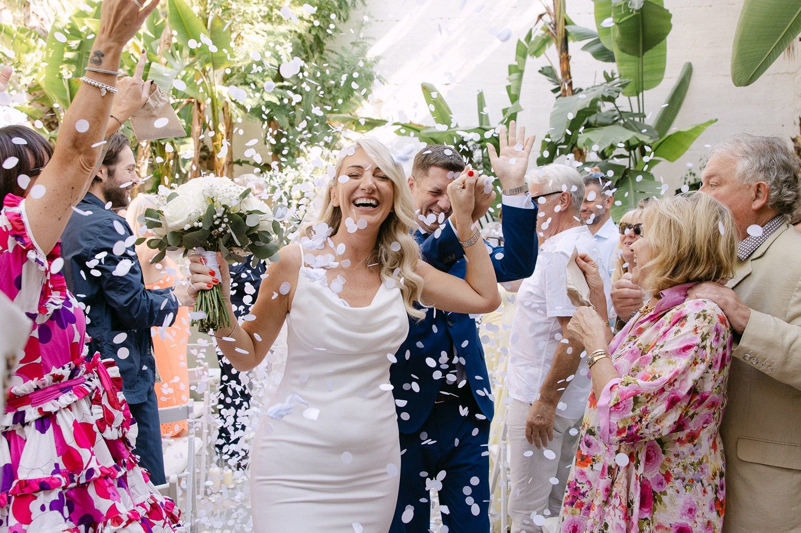 A couple celebrating with their guests in a shower of confetti